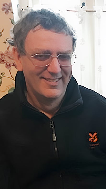 Image of a man dressed in a National Trust fleece sitting in a room in front of a window